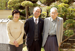 自宅の前で、妻の由実さん、養父の隆さんと。隆さんも熱心な生長の家の信仰者だ