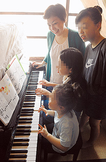 ピアノの練習の様子を見つめる和氣さん。「子どもたちの夢を、親として一所懸命、応援していきたいです」