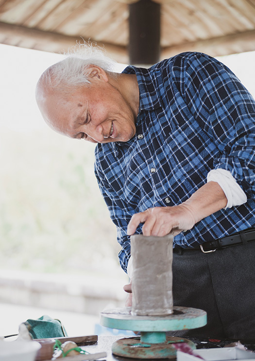 森田芳伯(ほうはく)さん│70歳│高知市 陶芸教室の生徒が作った花瓶を手直しする森田さん。熟練の業が冴える(高知城のそばにある城西公園にて) 取材/佐柄全一 写真/髙木あゆみ