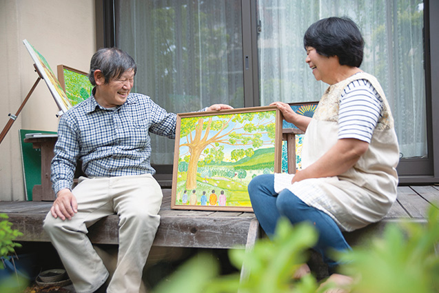 自宅の縁側で、妻の茂子さんと作品を眺めながら談笑する
