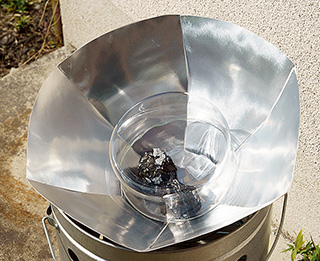 自作のソーラークッカー。材料が風で飛ばないようにガラス製の器をかぶせている