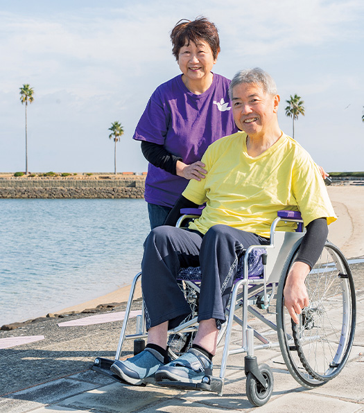 春の陽気に誘われて、近くの海岸まで出掛けた紫谷英幸さんと妻のゆかりさん。普段からよく二人で散歩をしているという。「私は明るい色が似合うんですよ！」と語る英幸さん（写真／髙木あゆみ）